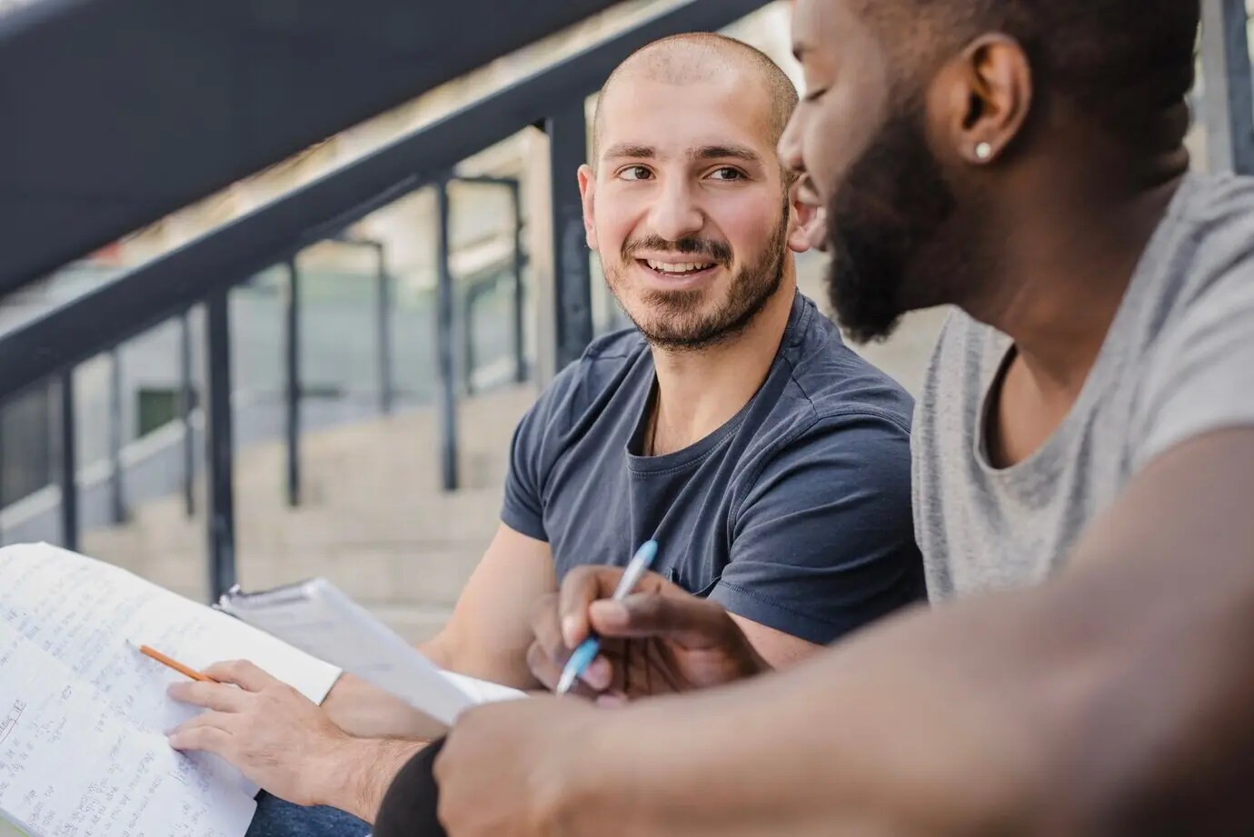 Zwei Studierende mit Papieren kommunizieren.